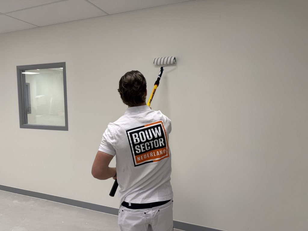 Schilder van Bouwsector Nederland rolt een lichte wand met een roller aan een verlengsteel